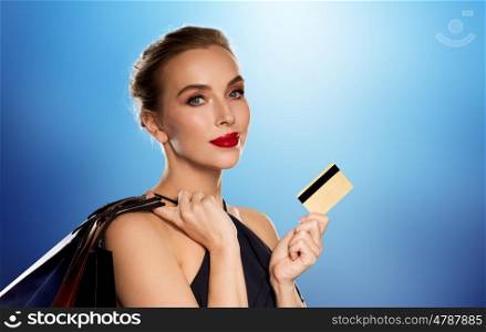people, luxury and sale concept - beautiful woman with credit card and shopping bags over blue background