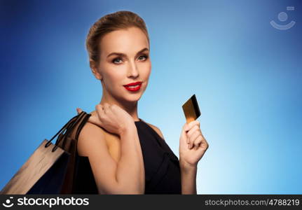 people, luxury and sale concept - beautiful woman with credit card and shopping bags over blue background