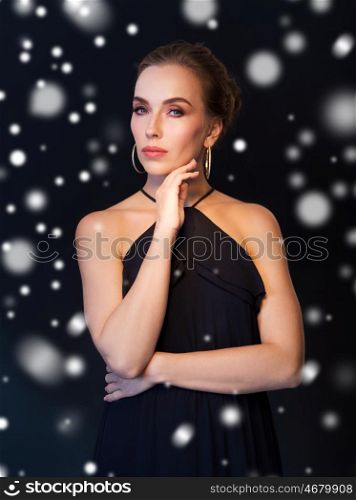 people, luxury, christmas, holidays and jewelry concept - beautiful woman wearing diamond earrings over black background and snow