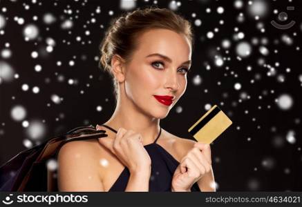 people, luxury, christmas, holidays and sale concept - beautiful woman with credit card and shopping bags over black background and snow