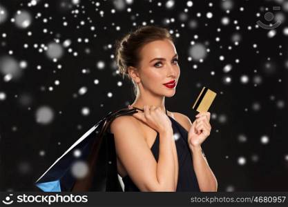 people, luxury, christmas, holidays and sale concept - beautiful woman with credit card and shopping bags over black background and snow