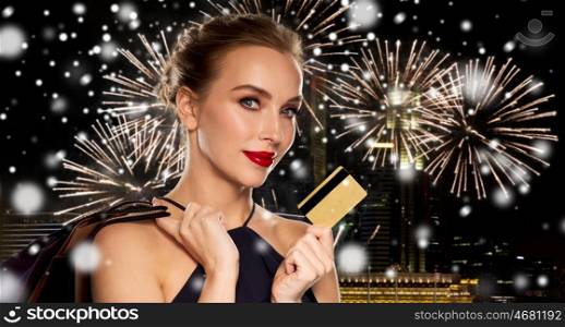 people, luxury, christmas, holidays and sale concept - beautiful woman with credit card and shopping bags over night singapore city and firework background and snow