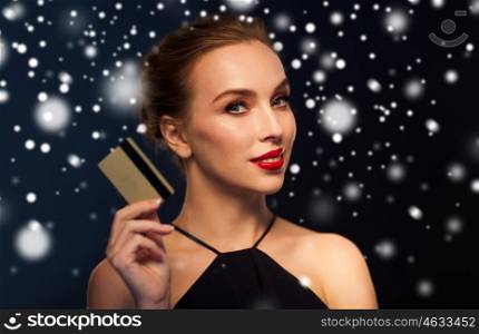 people, luxury, christmas, holidays and shopping concept - beautiful woman with credit card over black background and snow