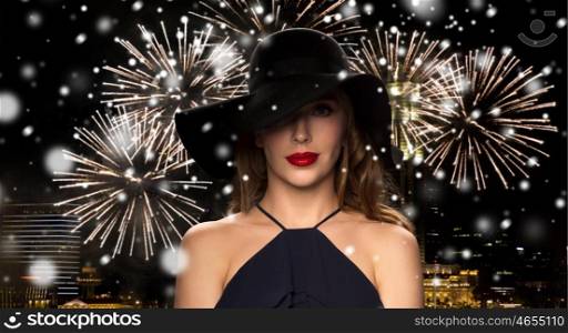people, luxury, christmas, new year and winter holidays concept - beautiful woman in black hat over night singapore city and firework background with snow
