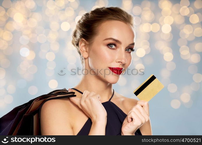 people, luxury, holidays and sale concept - beautiful woman with credit card and shopping bags over lights background
