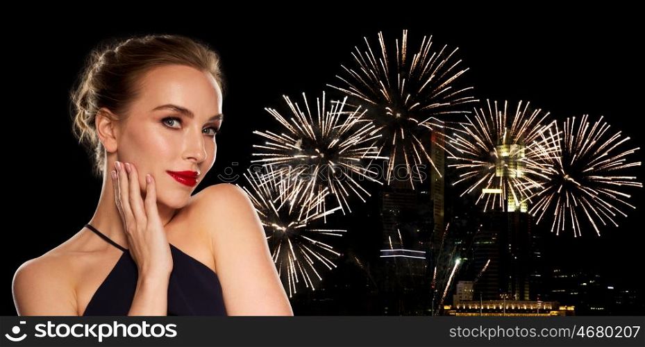 people, luxury, holidays, new year and fashion concept - beautiful woman in black with red lips over night city firework lights background