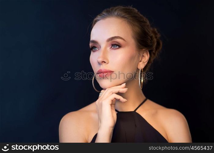 people, luxury, jewelry and fashion concept - beautiful woman in black wearing diamond earring and ring over dark background