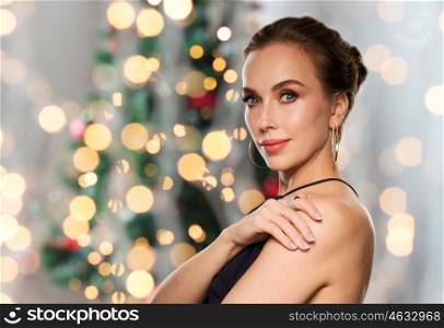 people, luxury, jewelry and fashion concept - beautiful woman in black wearing diamond earring and ring over lights background
