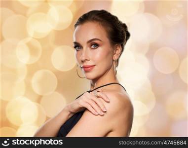 people, luxury, jewelry and fashion concept - beautiful woman in black wearing diamond earring and ring over lights background
