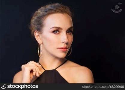 people, luxury, jewelry and fashion concept - beautiful woman in black wearing diamond earring and ring over dark background