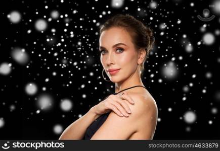 people, luxury, jewelry, christmas and holidays concept - beautiful woman wearing diamond earring and ring over black background and snow