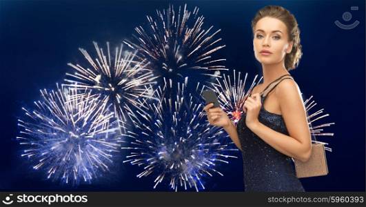 people, luxury, night life and finance concept - beautiful woman in evening dress with vip card and bag over firework on dark blue background