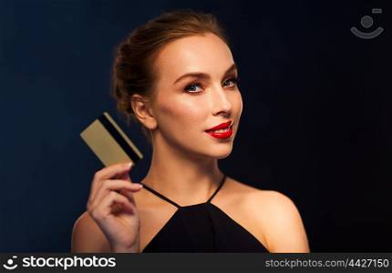 people, luxury, wealth, finances and shopping concept - beautiful woman with credit card over black background