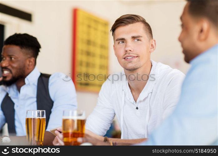 people, male friendship and communication concept - happy friends drinking beer at bar or pub. happy male friends drinking beer at bar or pub