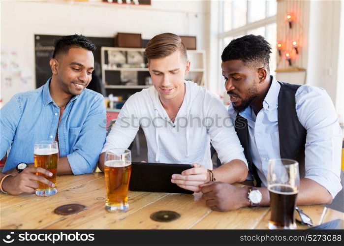 people, male friendship and technology concept - happy friends with tablet pc computer drinking beer at bar or pub. male friends with tablet pc drinking beer at bar