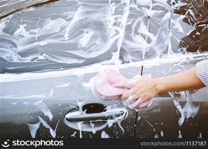 people man holding hand pink sponge for washing car. Concept car wash clean.