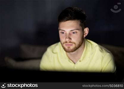 people, mass media, television and entertainment concept - young man watching tv at night at home. young man watching tv at night