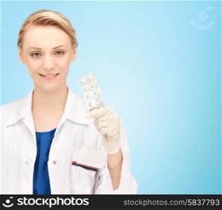 people, medicine, healthcare and medication concept - happy female doctor with pills over blue background