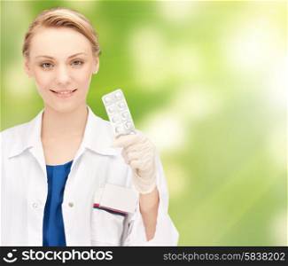 people, medicine, healthcare and medication concept - happy female doctor with pills over green background