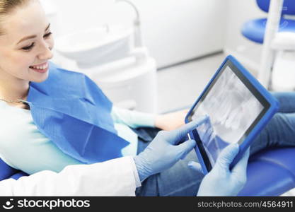 people, medicine, stomatology and health care concept - close up of dentist hands showing teeht x-ray on tablet pc computer to woman patient at dental clinic office