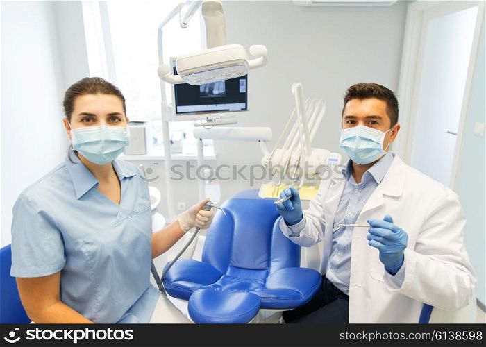 people, medicine, stomatology and health care concept - close up of dentist and assistant with dental mirror, drill and air water gun spray at dental clinic