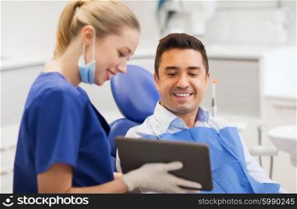 people, medicine, stomatology and health care concept - happy female dentist showing tablet pc computer to male patient at dental clinic office