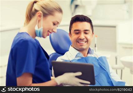 people, medicine, stomatology and health care concept - happy female dentist showing tablet pc computer to male patient at dental clinic office