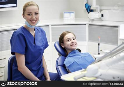 people, medicine, stomatology and health care concept - happy female dentist with patient girl at dental clinic office