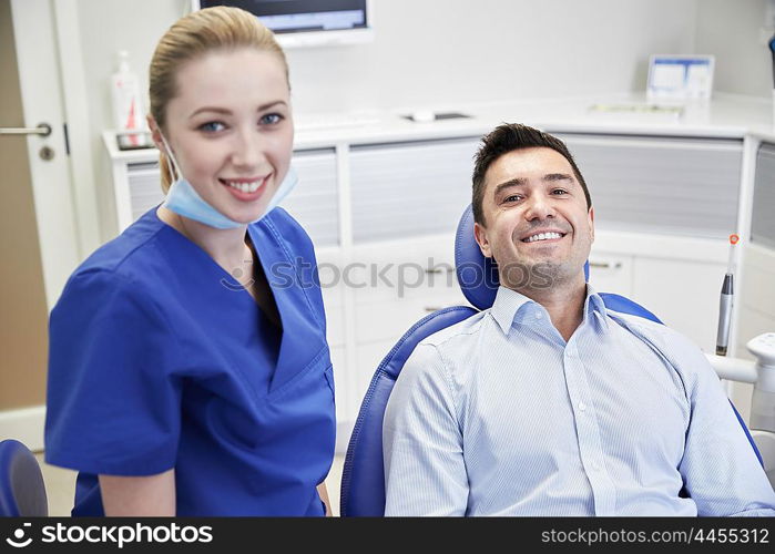 people, medicine, stomatology and health care concept - happy female dentist with man patient at dental clinic office