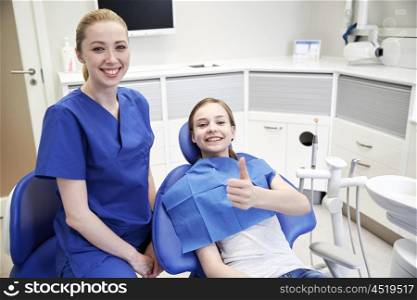 people, medicine, stomatology and health care concept - happy female dentist with patient girl at dental clinic office