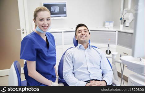 people, medicine, stomatology and health care concept - happy female dentist with man patient at dental clinic office