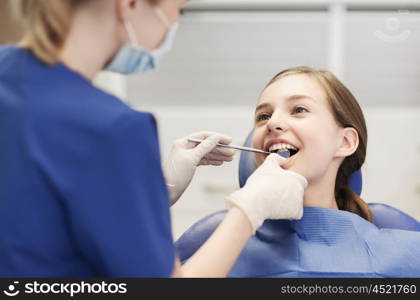 people, medicine, stomatology and health care concept - happy female dentist with mirror checking patient girl teeth up at dental clinic office