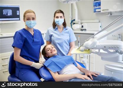 people, medicine, stomatology and health care concept - happy female dentist with assistant and patient girl at dental clinic office