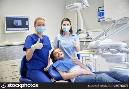 people, medicine, stomatology and health care concept - happy female dentist with assistant and patient girl at dental clinic office