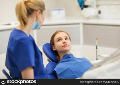 people, medicine, stomatology and health care concept - happy female dentist with patient girl talking at dental clinic office