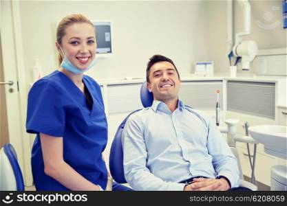 people, medicine, stomatology and health care concept - happy female dentist with man patient at dental clinic office