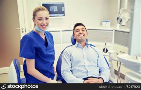 people, medicine, stomatology and health care concept - happy female dentist with man patient at dental clinic office