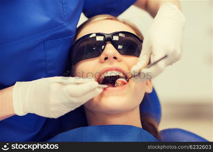 people, medicine, stomatology and health care concept - happy female dentist with mirror and probe checking patient girl teeth up at dental clinic office