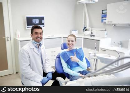 people, medicine, stomatology and health care concept - happy male dentist with woman patient talking at dental clinic office