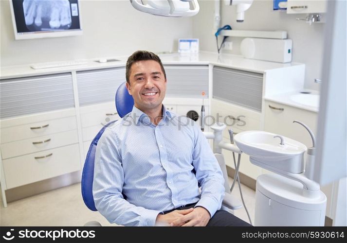 people, medicine, stomatology and health care concept - happy male patient sitting on dental chair at clinic office