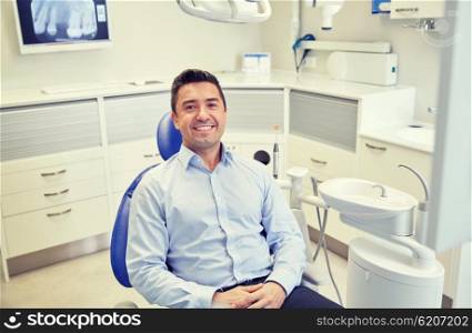people, medicine, stomatology and health care concept - happy male patient sitting on dental chair at clinic office
