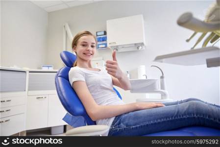 people, medicine, stomatology and health care concept - happy patient girl showing thumbs up at dental clinic office