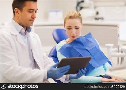 people, medicine, stomatology and health care concept - male dentist showing tablet pc computer to woman patient at dental clinic office