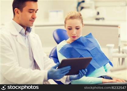 people, medicine, stomatology and health care concept - male dentist showing tablet pc computer to woman patient at dental clinic office