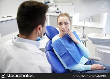 people, medicine, stomatology and health care concept - woman patient talking to male dentist and complain of toothache at dental clinic office
