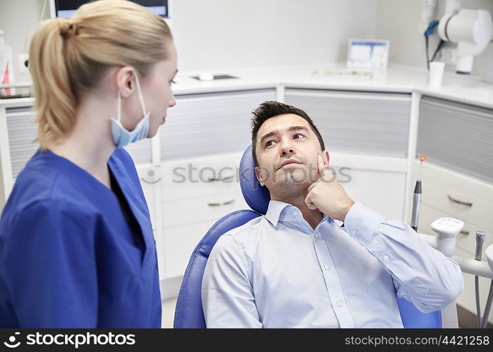 people, medicine, stomatology and health care concept - woman patient talking to male dentist and complain of toothache at dental clinic office