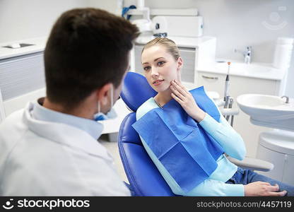 people, medicine, stomatology and health care concept - woman patient talking to male dentist and complain of toothache at dental clinic office