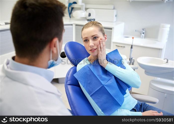 people, medicine, stomatology and health care concept - woman patient talking to male dentist and complain of toothache at dental clinic office
