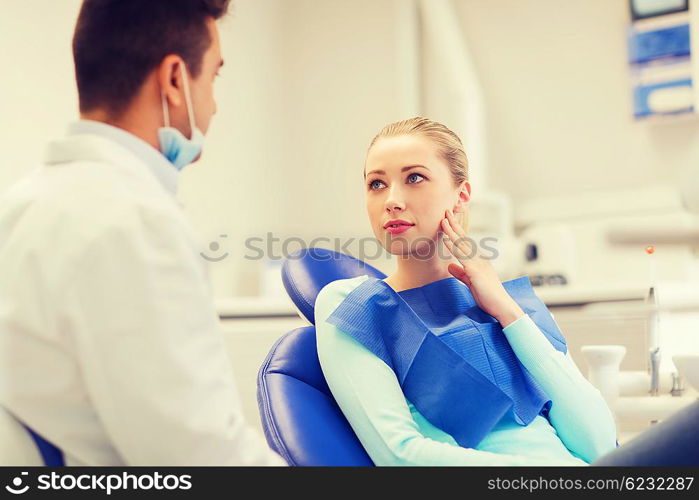 people, medicine, stomatology and health care concept - woman patient talking to male dentist and complain of toothache at dental clinic office