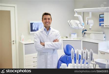 people, medicine, stomatology and healthcare concept - happy middle aged male dentist in white coat at dental clinic office